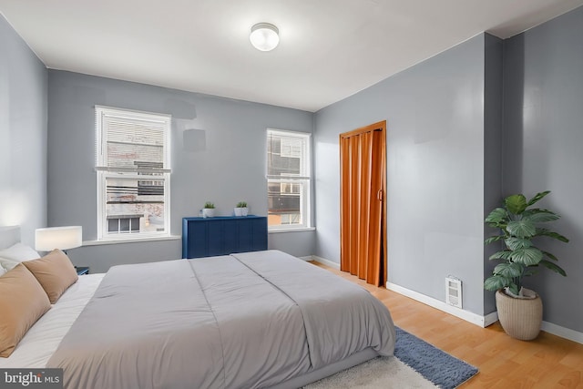 bedroom featuring wood finished floors, multiple windows, and baseboards
