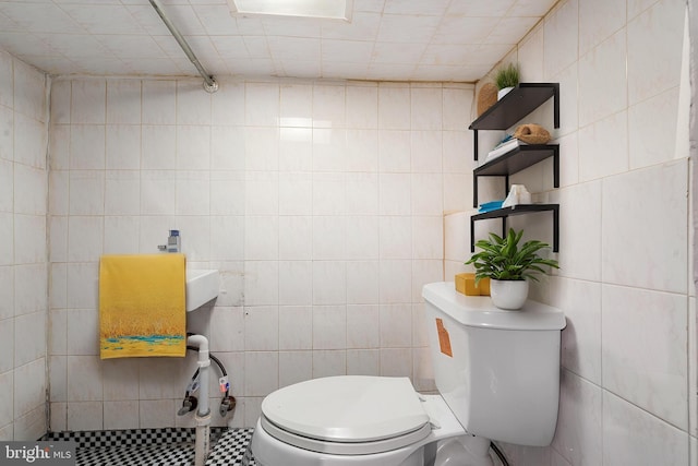 bathroom featuring tile walls and toilet