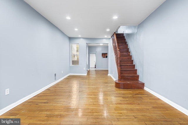 unfurnished living room featuring stairway, light wood-style flooring, recessed lighting, and baseboards