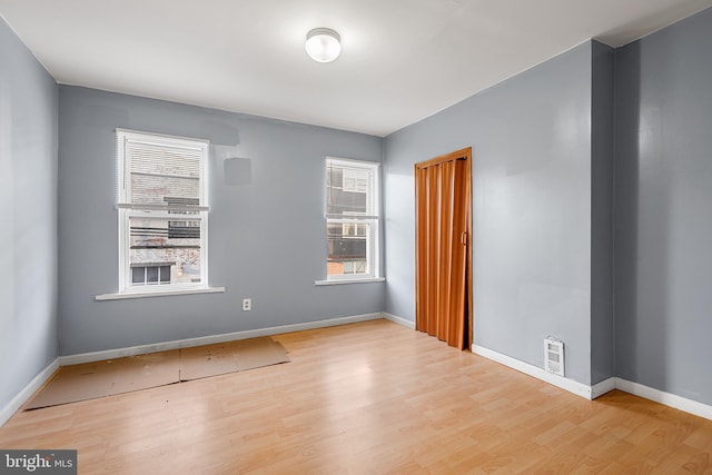 unfurnished room featuring healthy amount of natural light, wood finished floors, and baseboards