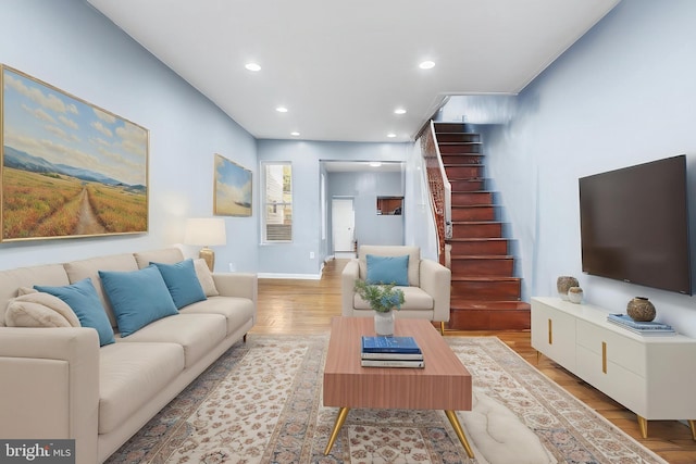 living area with recessed lighting, stairs, baseboards, and light wood finished floors