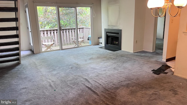 unfurnished living room with carpet flooring, a fireplace with flush hearth, a chandelier, and baseboards
