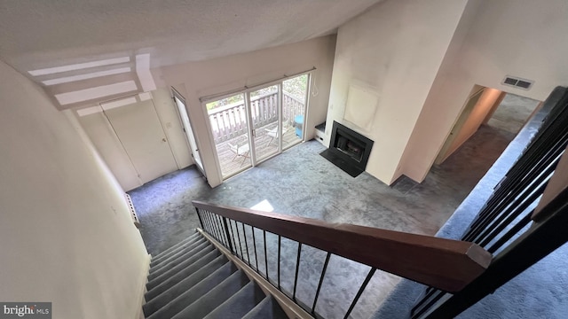 stairs with carpet floors and a fireplace with flush hearth