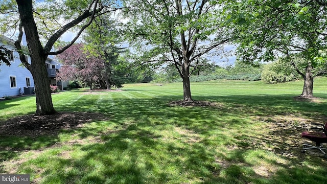 view of green lawn with central AC