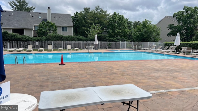community pool with a patio and fence