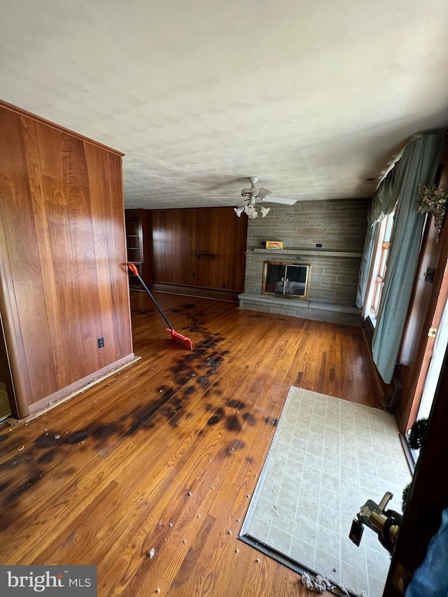 301 Ohio St, Boswell, PA 15531 - unfurnished living room with a large fireplace, hardwood / wood-style floors, ceiling fan, a baseboard radiator, and wood walls