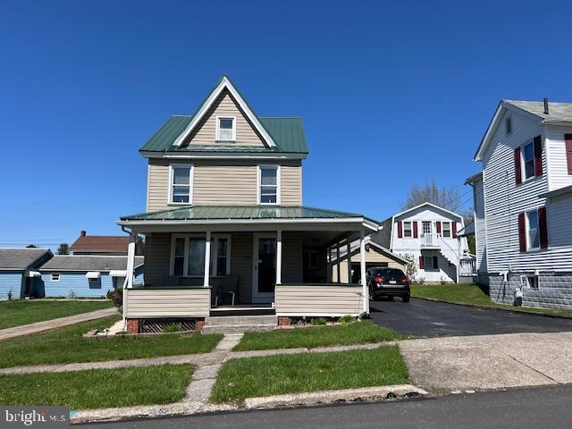 view of front of house with a porch, metal roof, and a front lawn