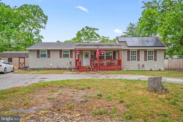 ranch-style house featuring covered porch and solar panels