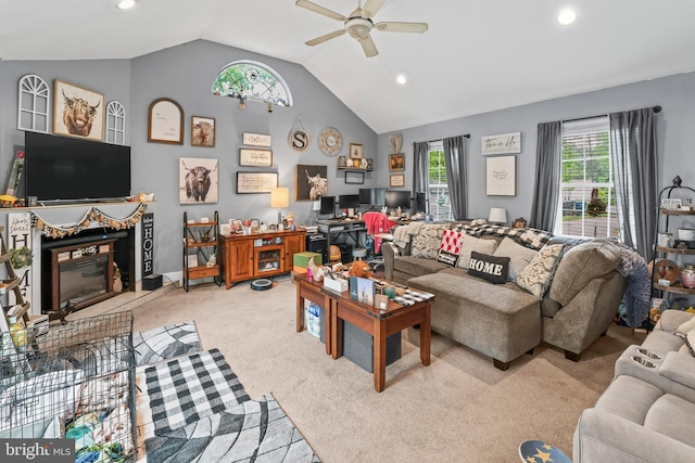 living room featuring lofted ceiling, a ceiling fan, recessed lighting, a glass covered fireplace, and light colored carpet