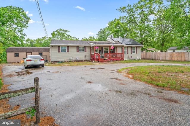 view of front of house with a porch, curved driveway, and fence