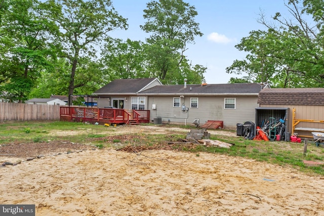 rear view of property featuring a deck, fence, central AC unit, a shed, and an outbuilding