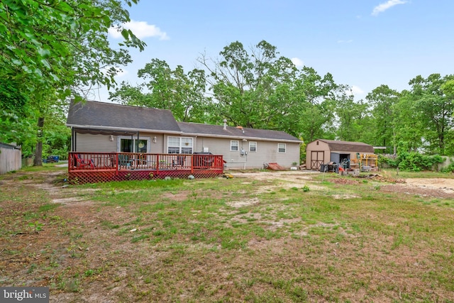 back of house with a storage shed, a deck, an outbuilding, and a lawn