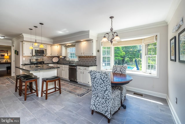 kitchen with stainless steel appliances, healthy amount of natural light, a chandelier, backsplash, and ornamental molding