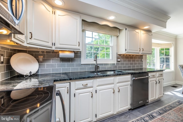 kitchen featuring appliances with stainless steel finishes, ornamental molding, plenty of natural light, white cabinets, and decorative backsplash