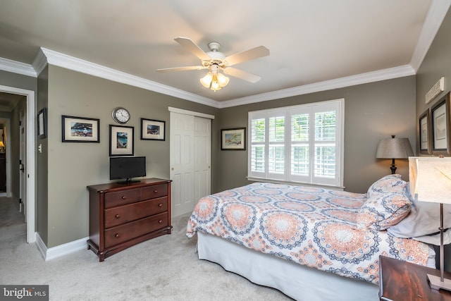 carpeted bedroom with a closet, ornamental molding, ceiling fan, and baseboards