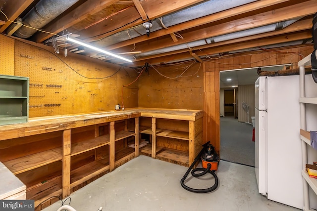 unfinished below grade area featuring a workshop area and freestanding refrigerator