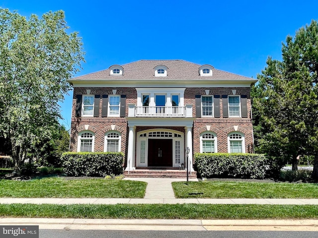 colonial home featuring a balcony, brick siding, and a front lawn