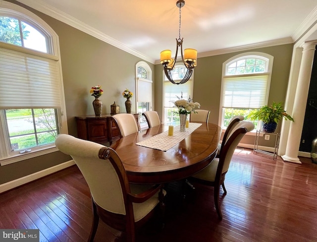 dining room with dark wood-type flooring, ornamental molding, a chandelier, baseboards, and ornate columns