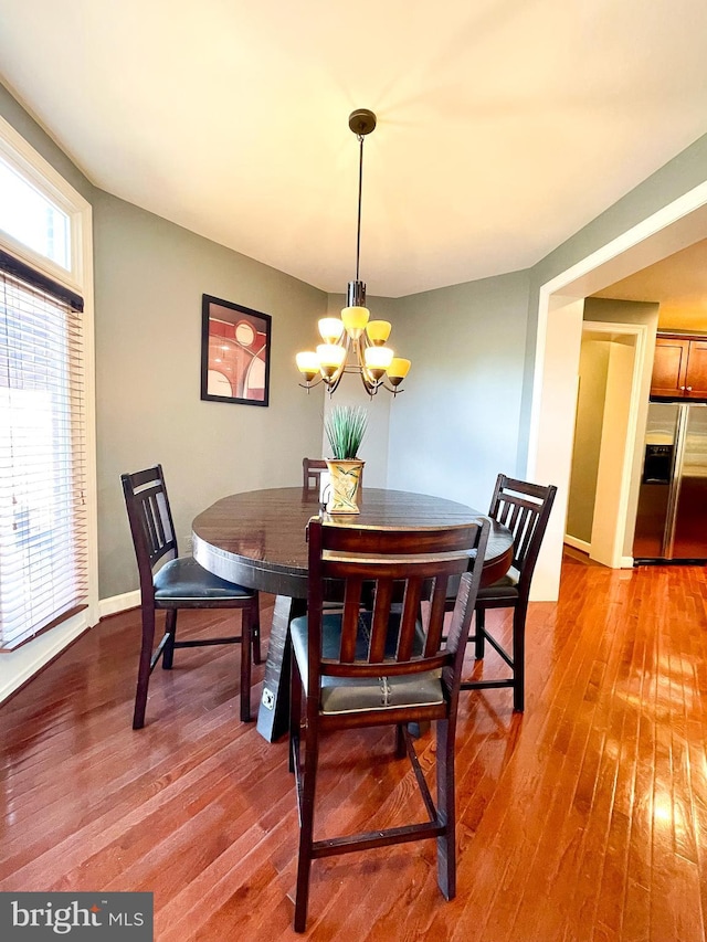 dining room with a chandelier, wood-type flooring, and baseboards