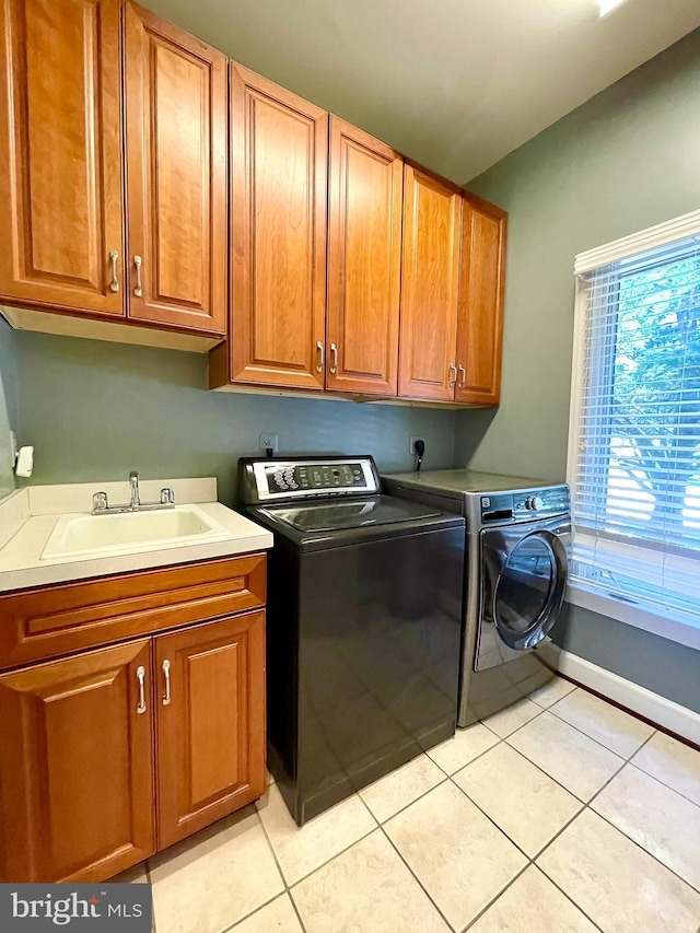 laundry room featuring washing machine and dryer, cabinet space, and light tile patterned floors