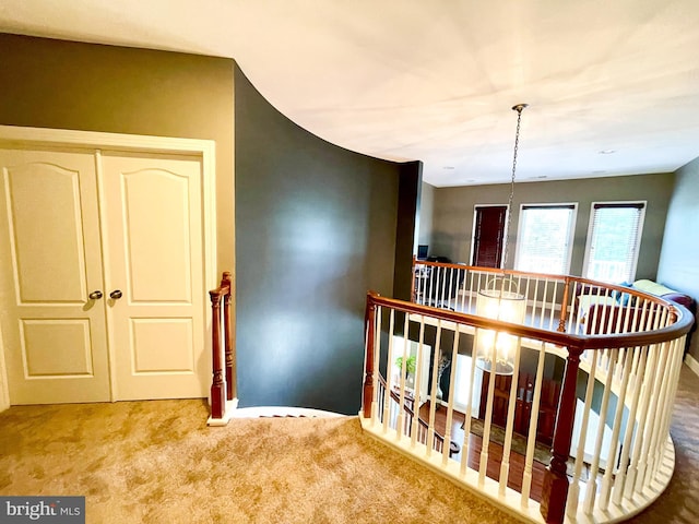 corridor with an upstairs landing and carpet