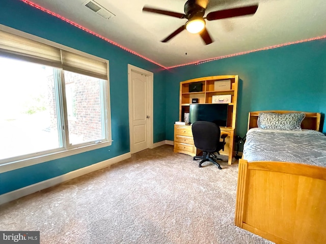 carpeted bedroom with multiple windows, baseboards, and ceiling fan