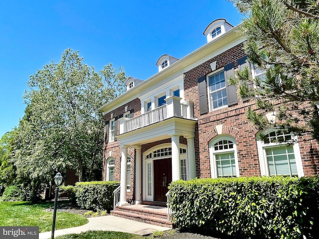 colonial house with a balcony and brick siding