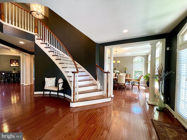 foyer entrance featuring stairs, wood-type flooring, a chandelier, decorative columns, and recessed lighting