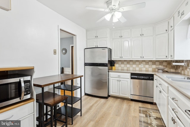 430 W Palmer St, Morrisville, PA 19067 - kitchen with appliances with stainless steel finishes, white cabinetry, light wood-type flooring, and decorative backsplash