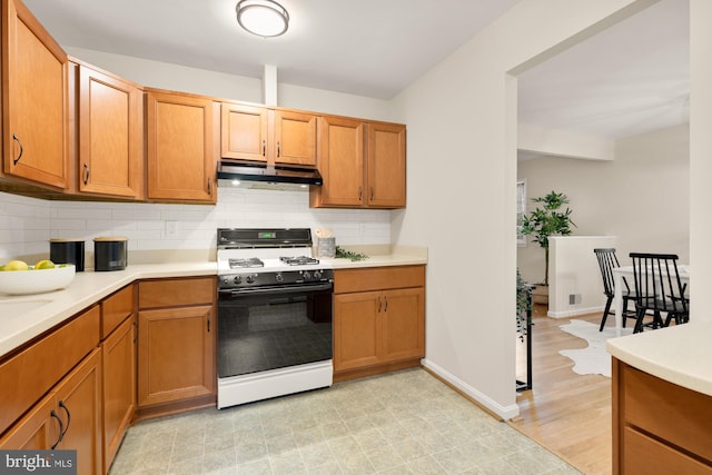 6008 Hawthorne St, Cheverly, MD 20785 - kitchen featuring white gas stove, under cabinet range hood, decorative backsplash, and light countertops
