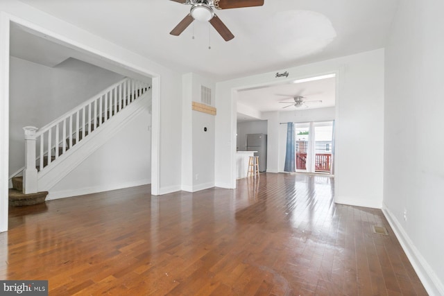 unfurnished living room featuring a ceiling fan, stairs, wood finished floors, and baseboards