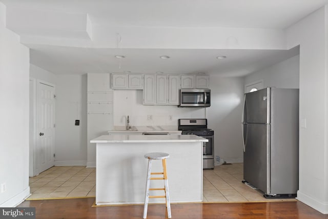 kitchen featuring stainless steel appliances, a sink, light countertops, light tile patterned flooring, and baseboards