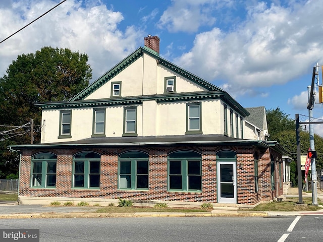 view of side of property with stucco siding, a chimney, and brick siding