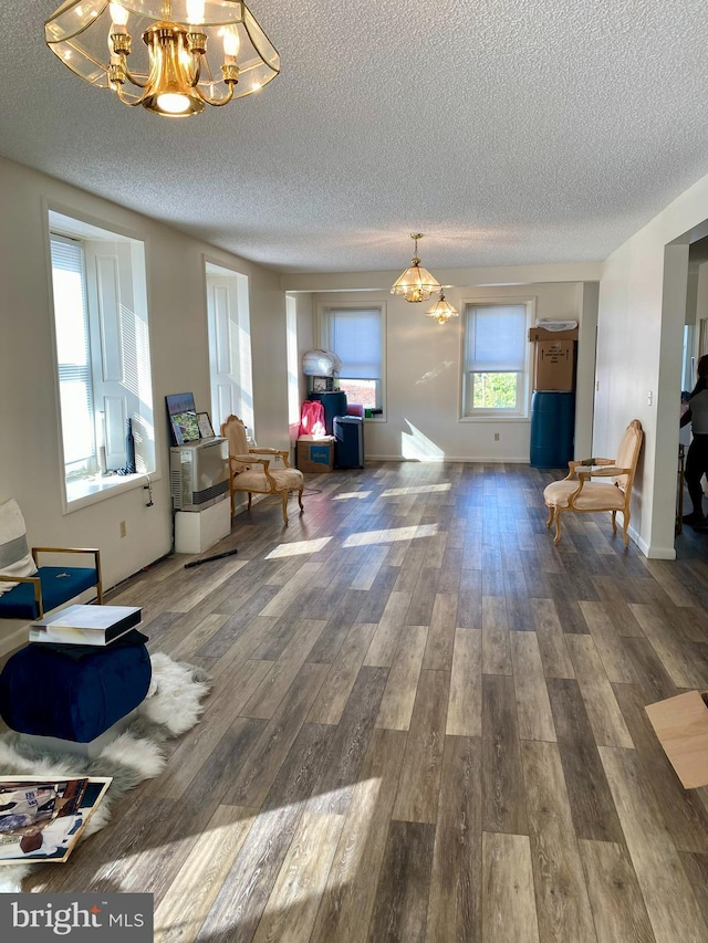 sitting room with a chandelier, a textured ceiling, wood finished floors, and baseboards