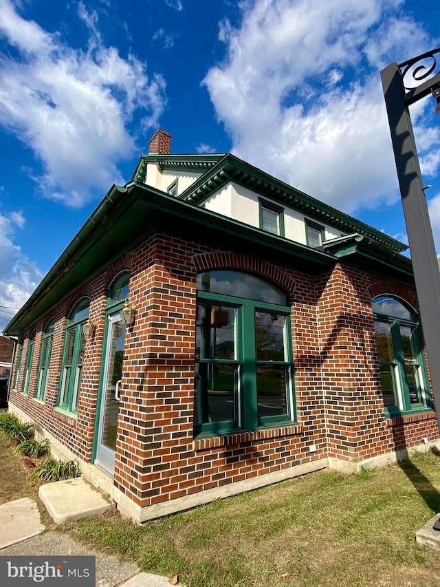 view of property exterior featuring brick siding and a chimney