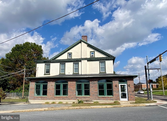 view of property exterior with stucco siding, fence, a chimney, and brick siding