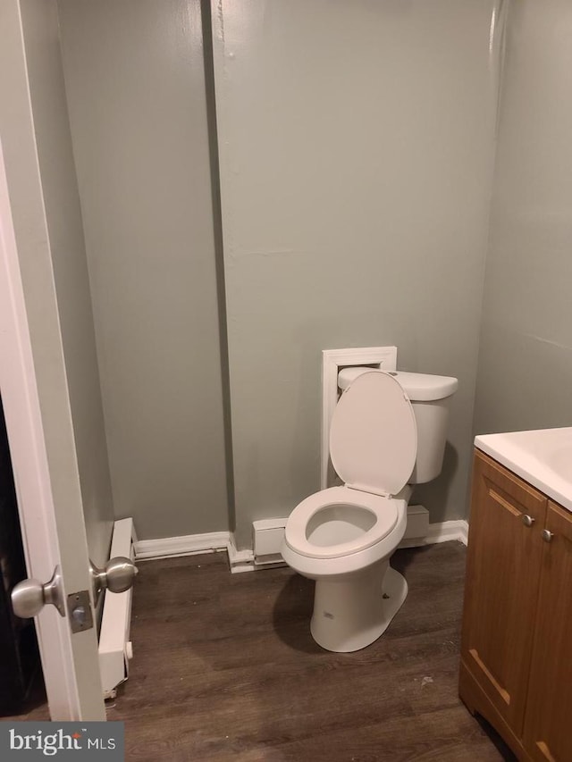 bathroom with wood finished floors, toilet, baseboards, and vanity
