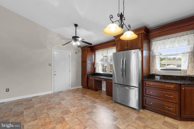 kitchen with freestanding refrigerator, baseboards, light stone finish flooring, healthy amount of natural light, and lofted ceiling