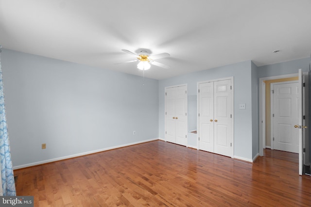 unfurnished bedroom featuring multiple closets, wood finished floors, and baseboards