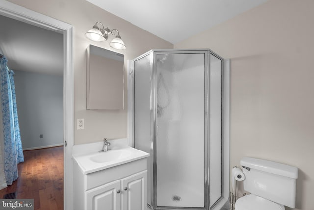 bathroom featuring a shower stall, vanity, toilet, and wood finished floors