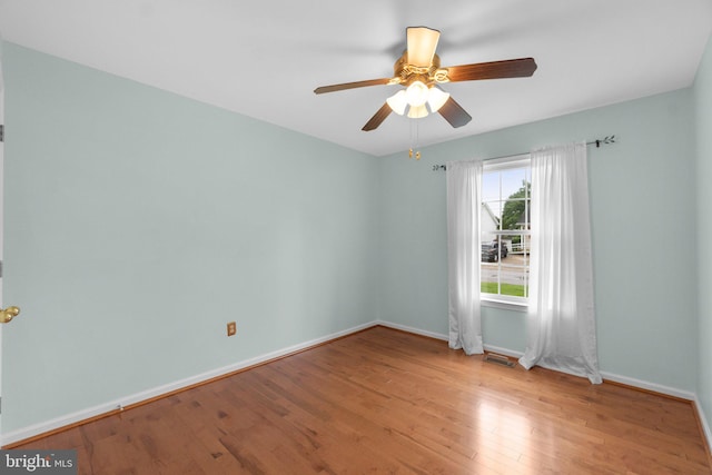 unfurnished room with wood finished floors, baseboards, and a ceiling fan