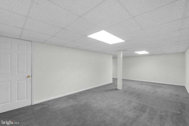 finished below grade area with dark colored carpet, a drop ceiling, and baseboards