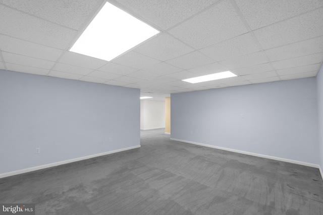 finished basement with dark carpet, baseboards, and a drop ceiling