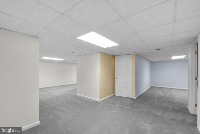 finished below grade area featuring carpet flooring, a drop ceiling, and baseboards
