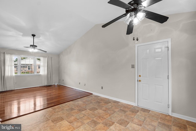 unfurnished living room with a ceiling fan, light stone finish floors, vaulted ceiling, and baseboards