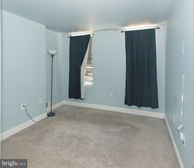 carpeted empty room featuring baseboards