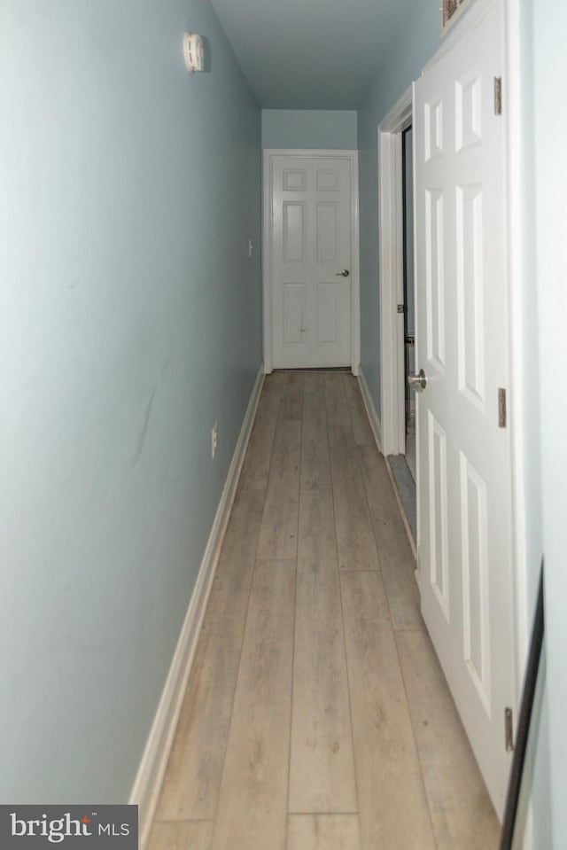 corridor featuring light wood-type flooring and baseboards