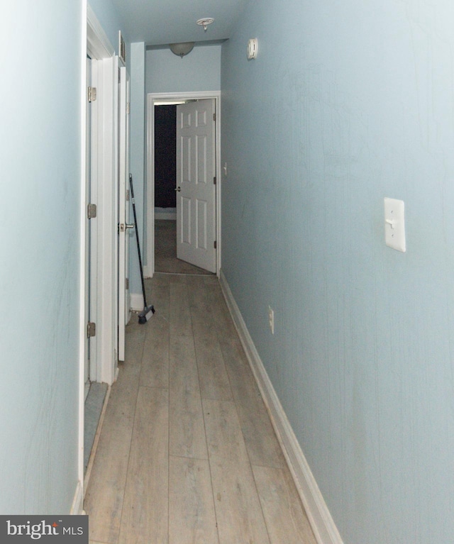 corridor with light wood finished floors and baseboards