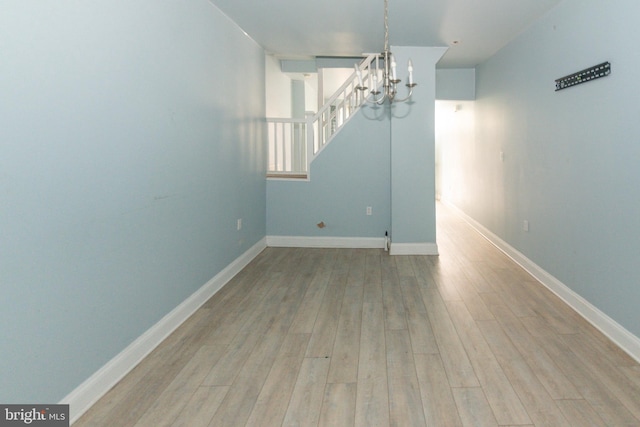 unfurnished dining area featuring a chandelier, wood finished floors, and baseboards