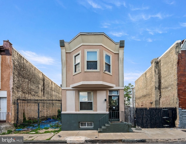view of front of home with stucco siding and fence